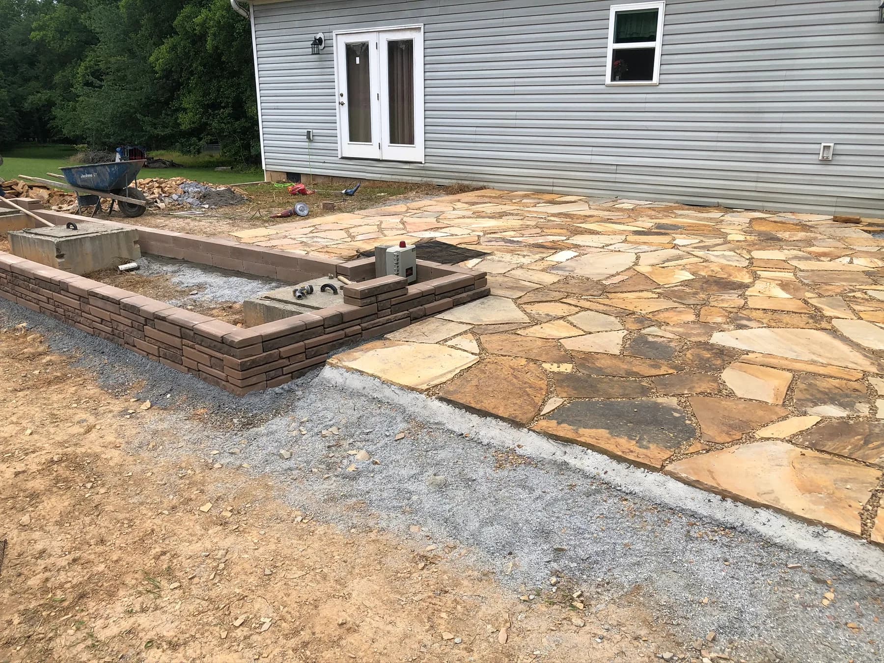 Natural stone patio with step transition and low wall work in progress, view 7