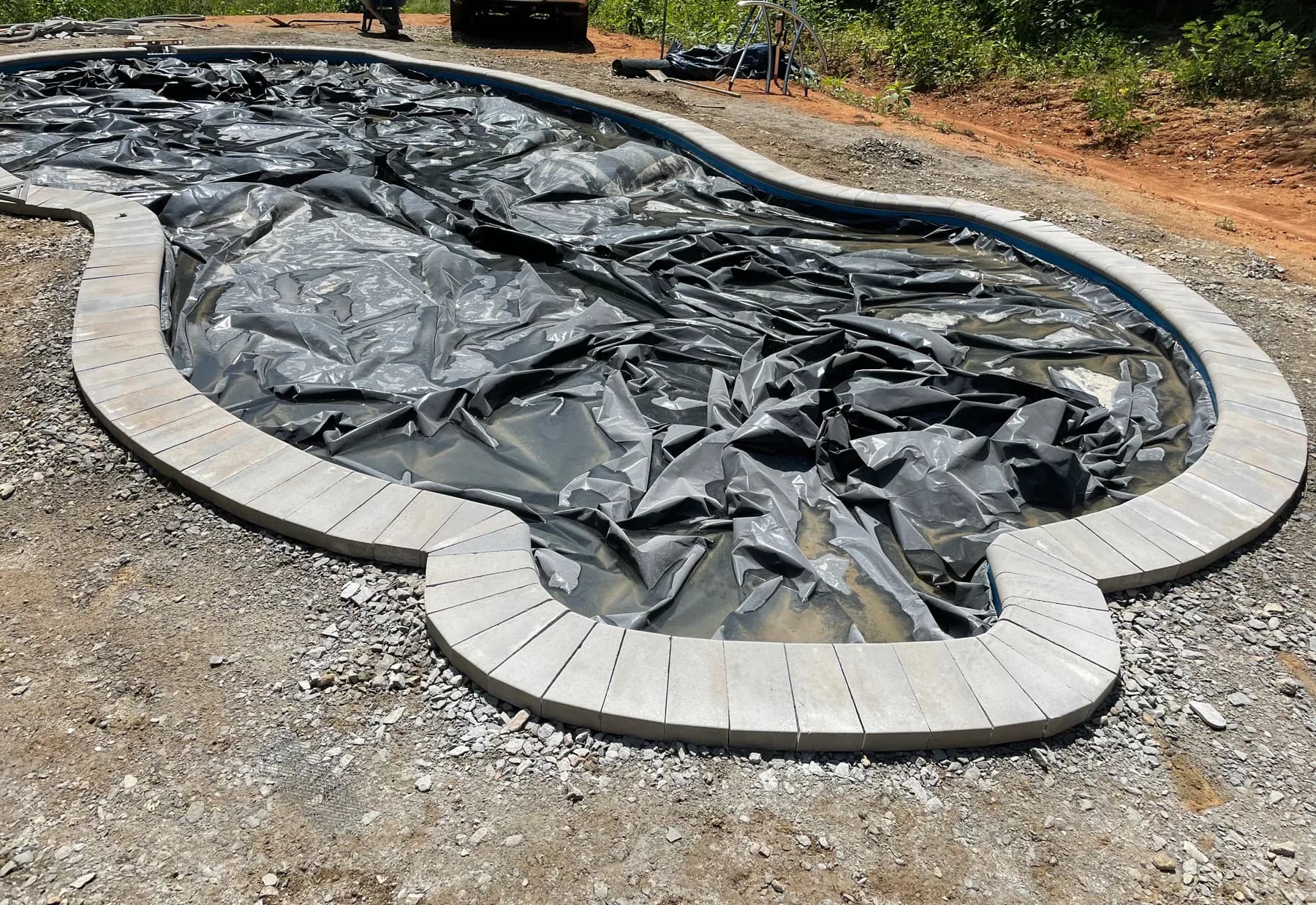 Poolside paver deck installation with border course and curved pool edge, view 4