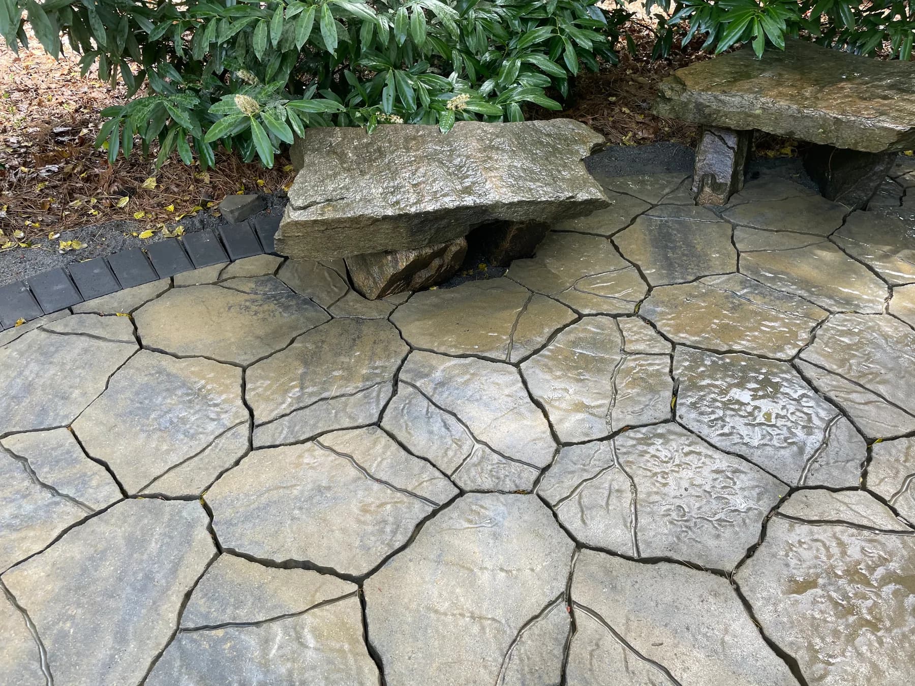 Woodland paver patio with natural stone seating tucked into a wooded edge, view 10